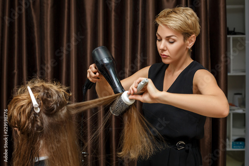 the hairdresser dries hair to the client with a Hairdryer