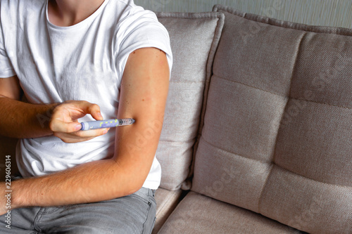 Fotografia close up of handsome stylish young teen caucasian with syringe inject insulin to his shoulder himself at home