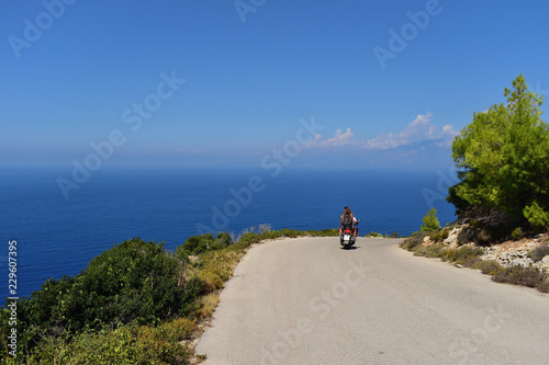Couple on motor scooter driving around Zakynthos Island, Greece