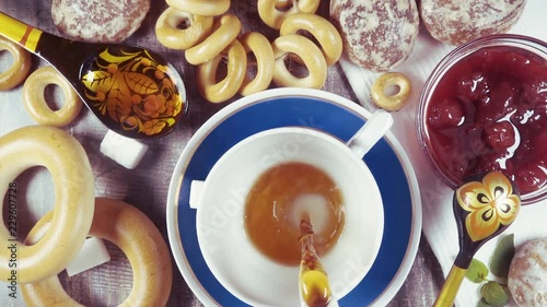 Slow motion traditional Russian tea party with Sushki, bagels Baranka and jam with gingerbread Pryanik top view photo