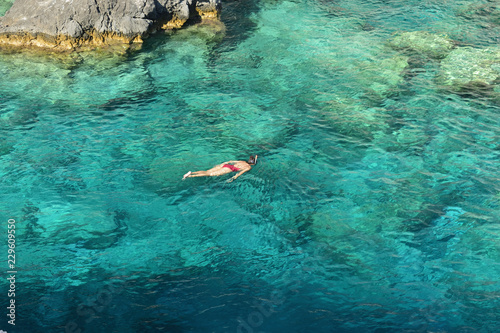 Young woman snorkeling in the turquoise waters at Plakaki Cape, Zakynthos Island, Greece photo