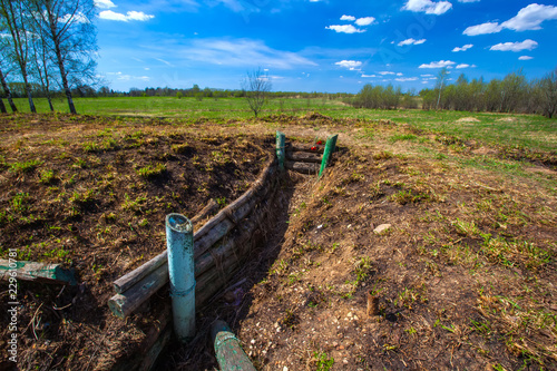 The deep trenches of the Second World War fortified with wood, red carnations in memory of the victims. Military trenches near the city of Volokolamsk at Dubosekovo junction, Moscow Region, Russia. photo