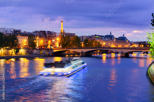 Pont Neuf and Cite island over Seine river with floating boat at night, France