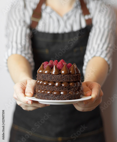 Chocolate naked cake with raspberry in the hands (front cake focus area)