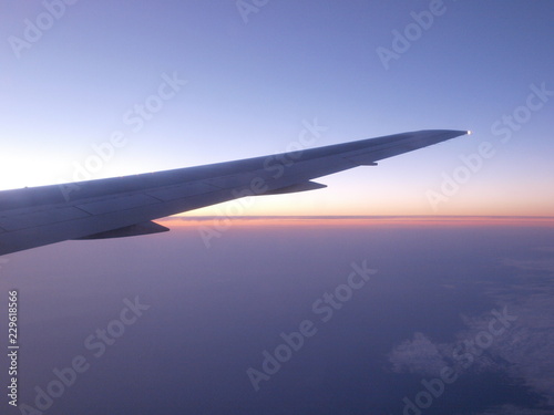 Beautiful sunset in purple and blue tones with cloudy sky from the airplane window.