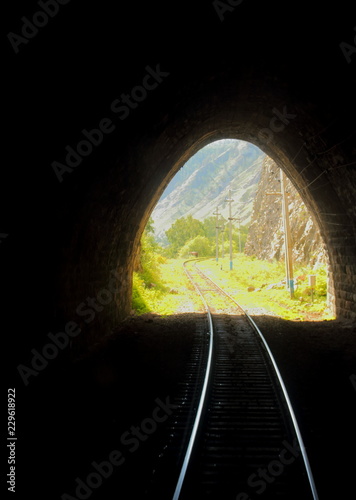 Bright sunny escape from dark old stone mountain tunnel on the Circum-Baikal railway. Background of a summer landscape for travel in Siberia. Conceptual background of there is always a way out.