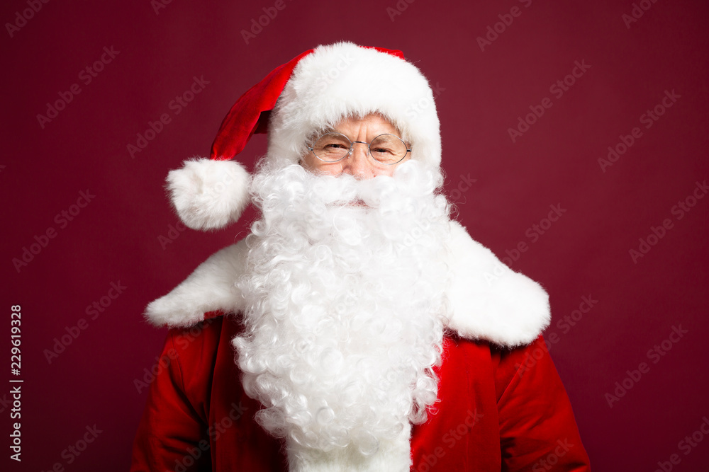 Portrait of man in Santa Clause costume looking at camera while posing on red background, Christmas and New year concept Portrait of man in Santa Clause costume looking at camera while posing on red background, Christmas and New year concept