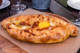 Adjaran open khachapuri. Traditional Caucasian pie shaped boat baked with cheese in oven and topped raw egg and butter