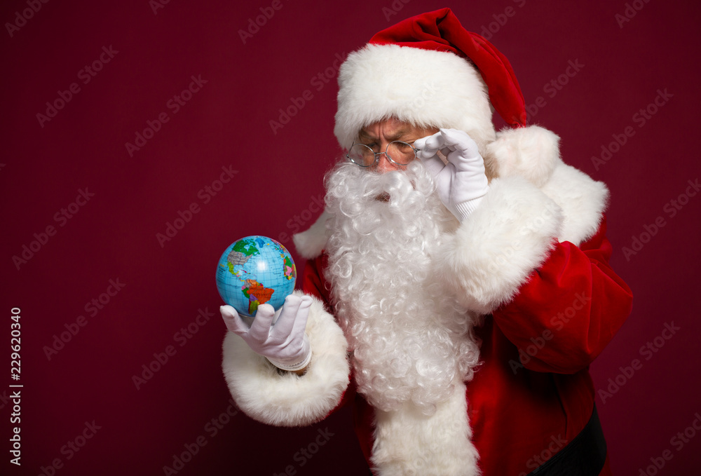 Santa Clause with earth globe on hand on red background, Christmas and New year concept