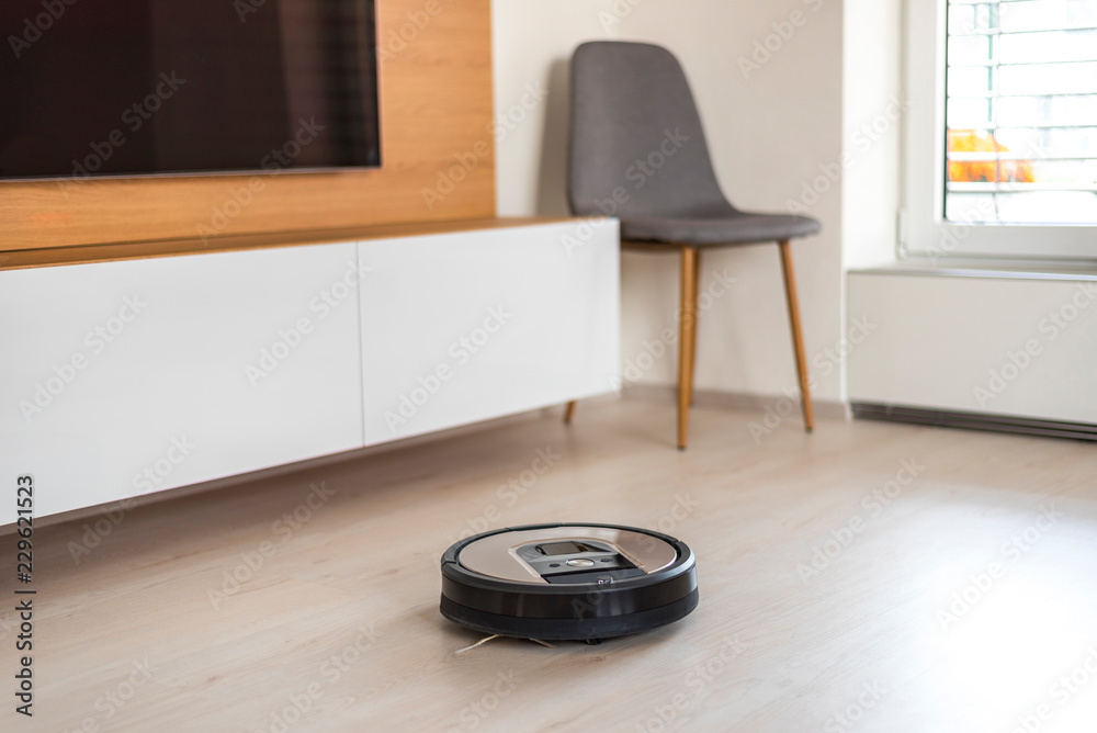 Automated vacuum cleaning robot powered by rechargeable battery in modern living room Automated vacuum cleaning robot powered by rechargeable battery in modern living room