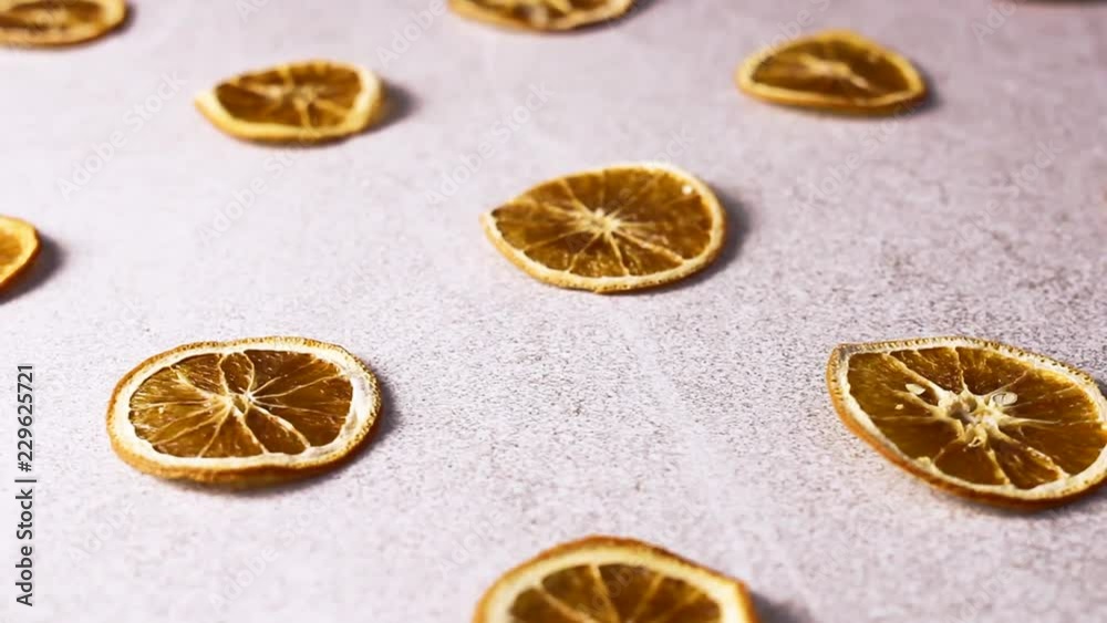 Dried sliced orange and lemon rotating on white texture surface.