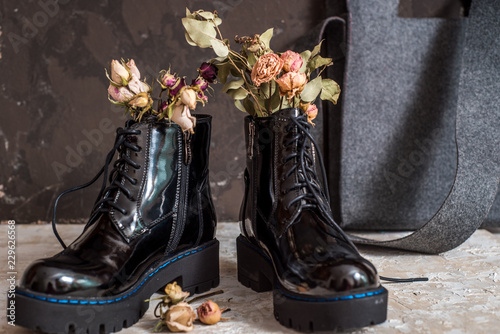 Yellow flowers grow in the old black boots for original decorate photo