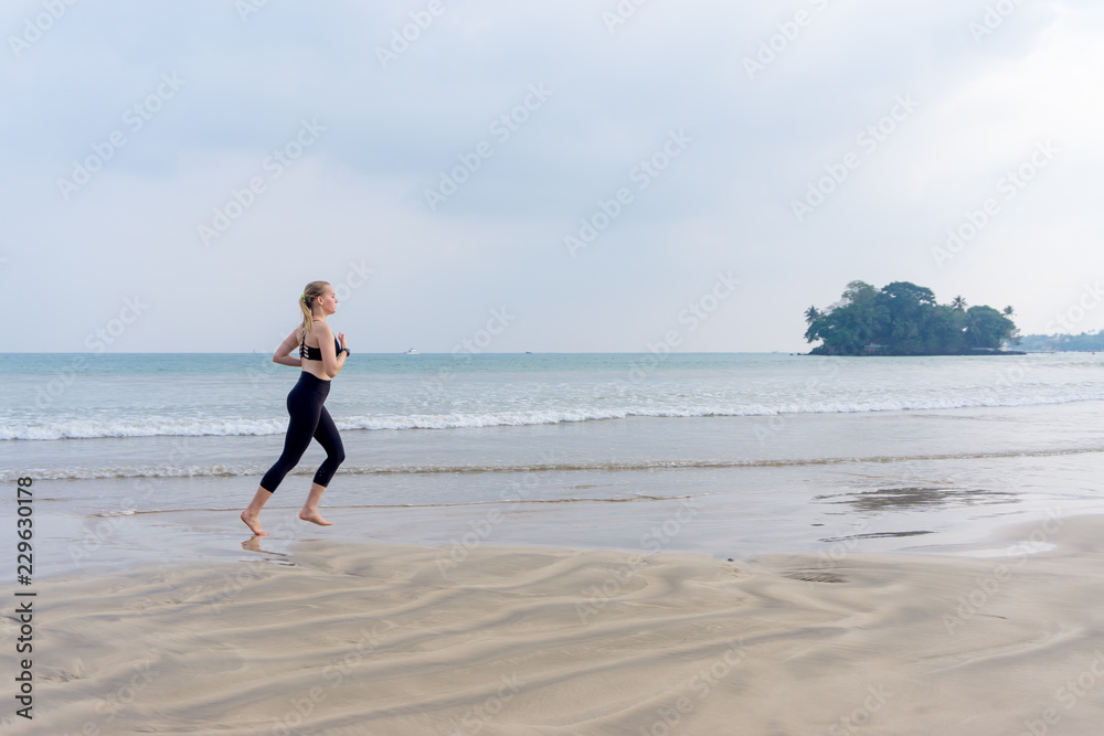 The girl runs along the beach doing sports