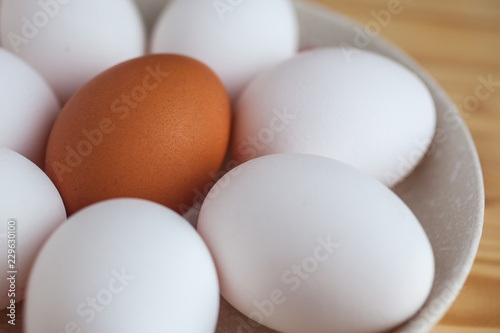 One brown and white eggs in a ceramic dish on a wooden table