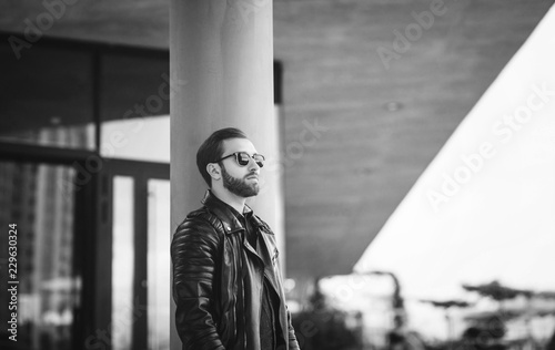 black and white portrait of a stylish man in a leather jacket on the street