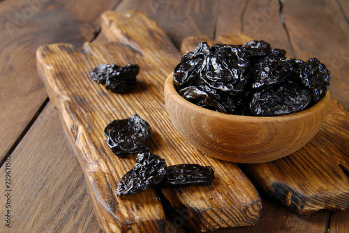 Dry plum in a wooden bowl on the table. photo