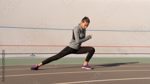 Young brunette woman makes sport exercices on the running track, outdoors