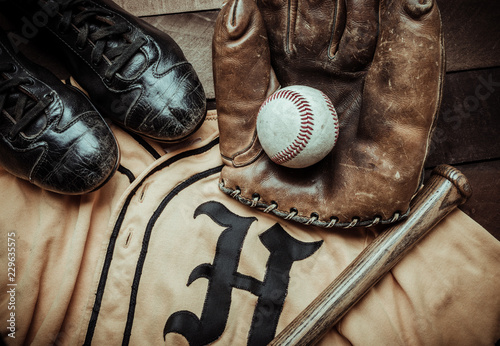 Photography A group of vintage baseball equipment, bats, gloves, baseballsand a jersey on wo