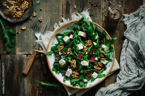 Salad with beets, walnuts, feta cheese and arugula. Rustic style salad on a dark wooden background