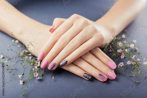 Pink and black manicure with flowers on grey background. Nail art