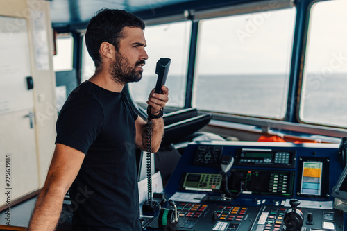 Marine navigational officer is reporting by VHF radio during navigation watch. Bridge GMDSS watch