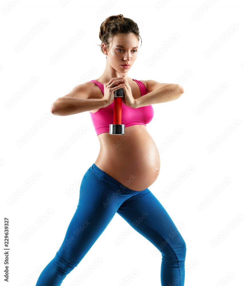 Fototapeta premium Sporty pregnant woman doing exercises with dumbbell isolated on white background. Concept of healthy life