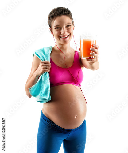 Resting time. Pregnant woman in sportswear holding towel and glass of orange juice isolated on white background. Concept of healthy life