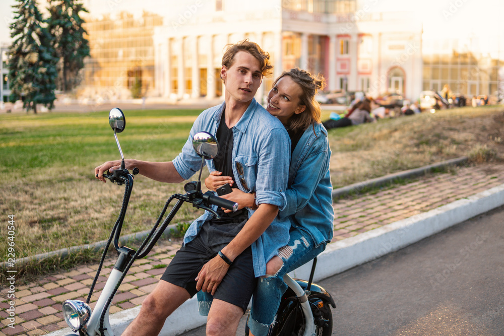 Obraz premium Lovely young couple driving electric bike during summer. Modern city dating and transportation