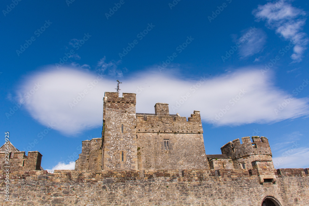 Medieval stone castle against a blue sky with one large white cloud