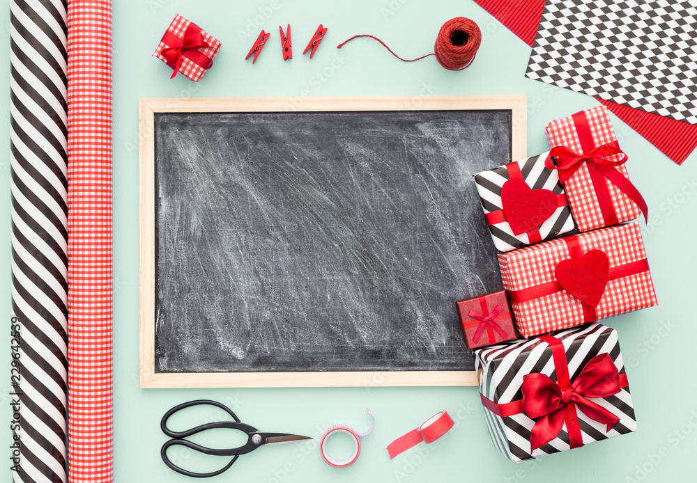 Chalkboard and presents wrapped on a mint color background with different on a pink color table. Flat lay.Christmas (xmas) or New year gift packing. Holiday decor concept. Chalkboard and presents wrapped on a mint color background with different on a pink color table. Flat lay.Christmas (xmas) or New year gift packing. Holiday decor concept.