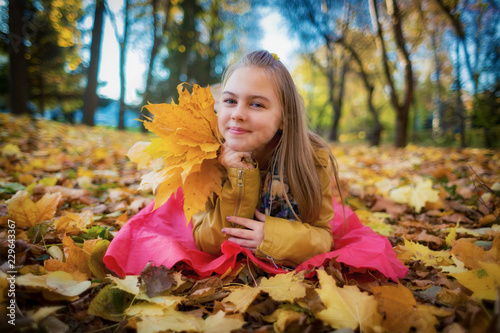 Girl lying with yellow leaves in autumn Park