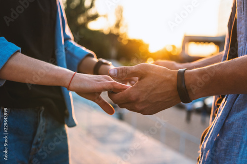 Closeup view of hands of lovely young couple dating during summer sunset. they wear jeans clothes. modern youth relationship