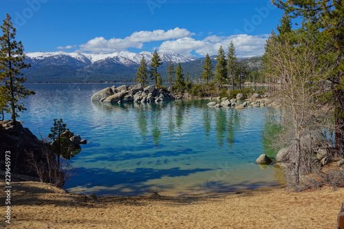 Beautiful view of a sandy beach leading toward the emerald lake by the mountains