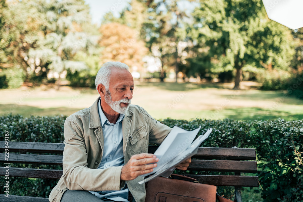 Fototapeta premium Retired man reading newspapers in the park.
