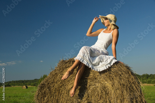 beautiful young girl at a haystack in a summer field