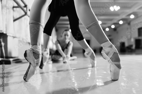 Fototapeta Naklejka Na Ścianę i Meble -  feet of young ballerinas in pointe shoes close-up against the backdrop of a ballet class