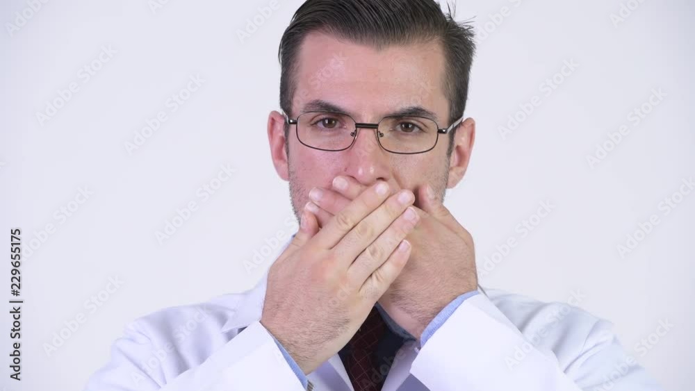 Young Hispanic man doctor covering mouth as three wise monkeys concept Young Hispanic man doctor covering mouth as three wise monkeys concept