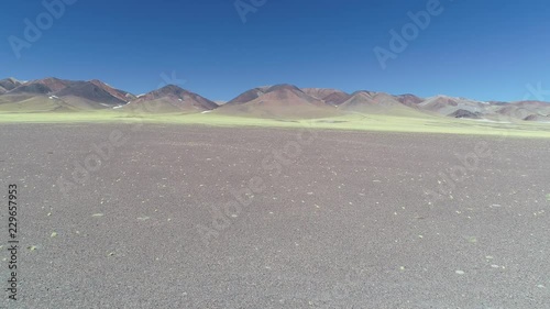 Aerial drone scene of rocky eroded colorful mountains with yellow vegetation in front. Catamarca, Argentina. Flying towards hills. photo