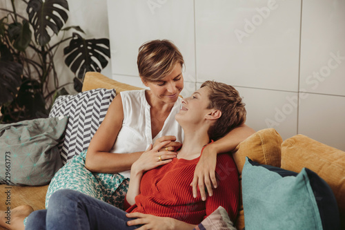 Happy lesbian couple cuddling on couch