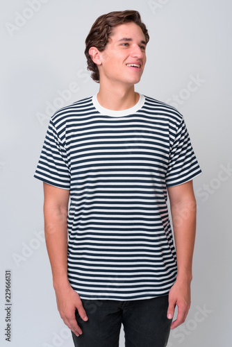 Young handsome man with wavy hair against white background © Ranta Images