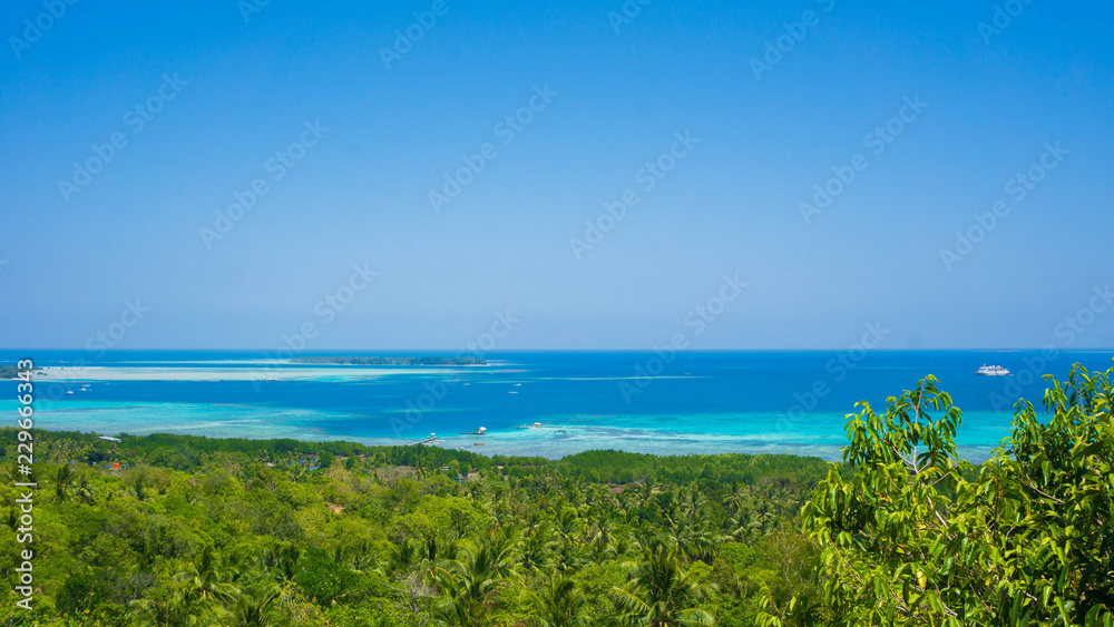 a forest and deep blue sea view from bukit love