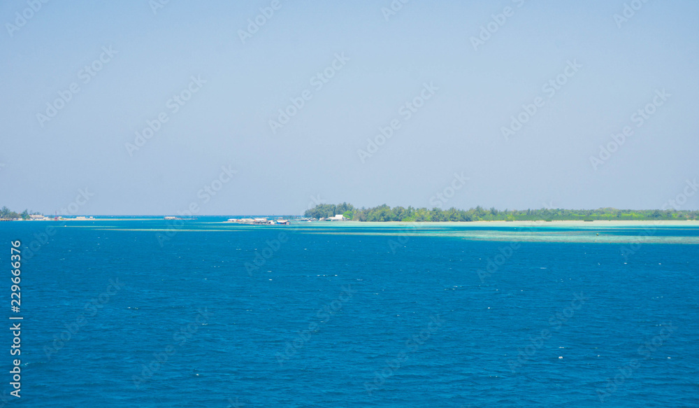 an island with deep blue sea with traditional house on the island in distance