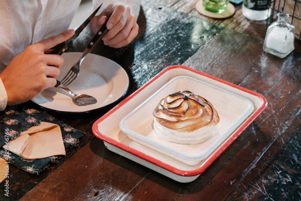 Fototapeta premium Asian man Eat Fine dining dessert, burnt ice cream in white vintage plate over wooden table