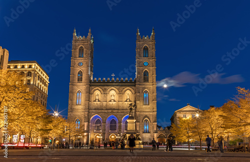 Montreal, Canada, October 20, 2018. Notre Dame Basilica from Montreal and Maisonneuve Monument illuminated at night time, during autumn season.  First neo-gothic church in Canada. photo