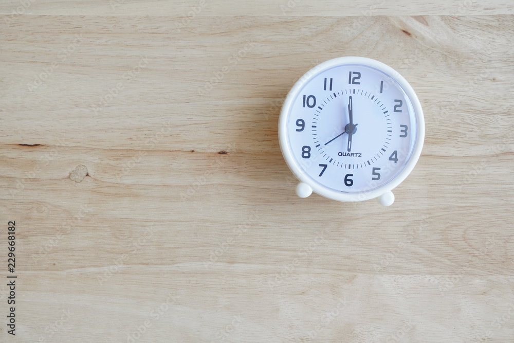 white circle clock on light brown wood background , morning wake up concept white circle clock on light brown wood background , morning wake up concept