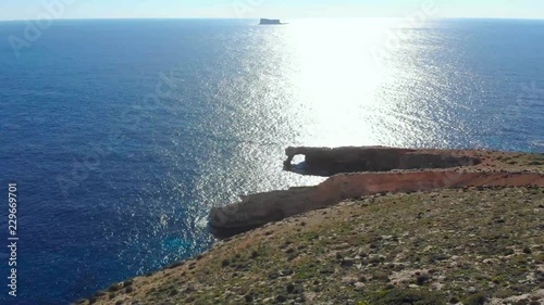 Drone shot over rocks in nature and towards a stone window and a Filfla - a small island in the Mediterranean sea of Malta photo