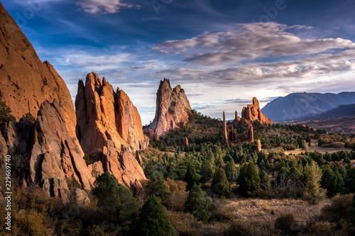 Picturesque scene within the Garden of the Gods national park in Colorado Springs, Colorado. There are jagged red sandstone rocks erupting from the ground reaching for the sky. 
