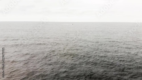 Aerial shot of one lone motor boat speeding through the endless waves of the open ocean. photo