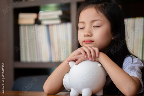 cute girl tired sleep on piggy bank,saving money concept photo