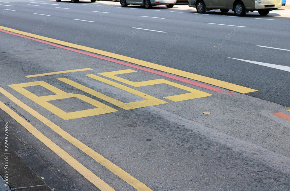 Colourful yellow and red bus lane for public transport road markings on a grey paved street in Singapore, Southeast Asia